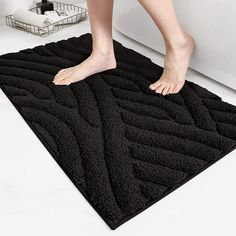 a person standing on top of a black bath mat