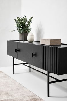 a black and white sideboard with two vases sitting on it's sides