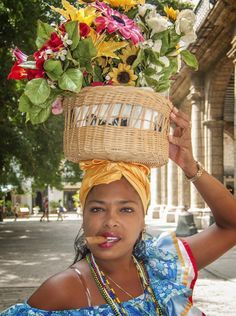 a woman with a basket full of flowers on her head