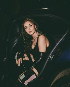 a woman sitting in the back seat of a car wearing black leather gloves and stockings