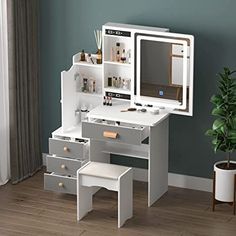 a white desk with drawers and a mirror on it next to a potted plant