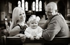 a man, woman and baby sitting on a pew in a church