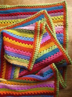 multicolored crocheted blanket folded on wooden surface