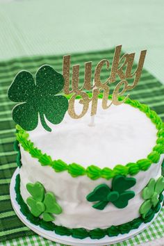 a green and white cake with shamrocks on it that says lucky one in gold letters