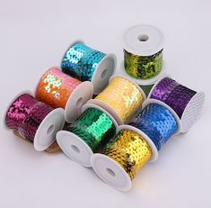 several spools of sequinized ribbon in various colors and sizes on a white background