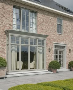 a brick house with large windows and two chairs