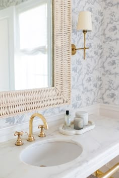 a white sink sitting under a bathroom mirror next to a wall mounted faucet