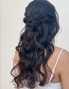 the back of a woman's head with long dark hair, wearing a white tank top