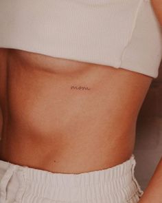 a woman's stomach with the word mom tattooed on her left side ribcage