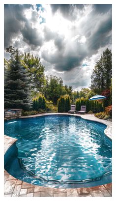 an empty swimming pool surrounded by greenery and trees under a cloudy sky with sun shining through the clouds