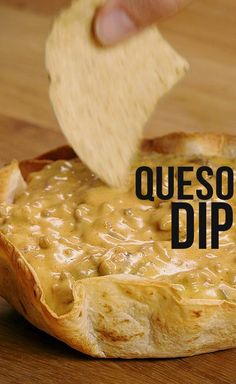 a hand dipping a tortilla chip into a dip