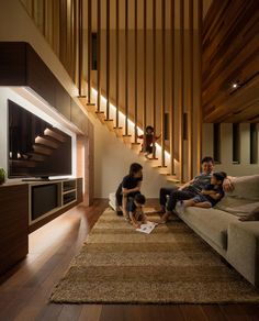 two people sitting on a couch in front of a stair case with wooden slats