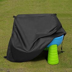 a black cover sitting on top of a green field next to a blue and yellow frisbee