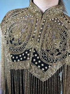 the back of a woman's dress with gold beading and fringes on it