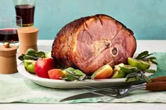 a ham is sitting on a plate with apples and other fruit