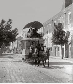 an old black and white photo of people riding in a horse drawn carriage