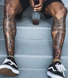 a man with tattoos sitting on steps holding a drink