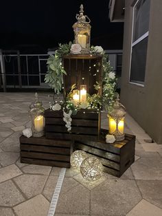 candles are lit in front of some wooden crates with flowers and greenery on them