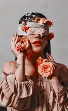 a woman with flowers on her head holding roses in front of her face