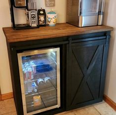 a small refrigerator and coffee maker on top of a wooden cabinet in a room with tile flooring