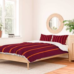 a bed with red and orange striped comforter in a white room next to a window