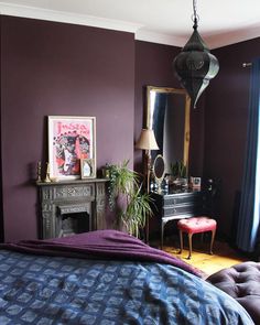 a bedroom with purple walls and a blue comforter on the bed, next to a fireplace