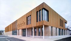 an empty parking lot in front of a large building with wooden panels on the side