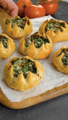 some bread with spinach and cheese in it on a cutting board next to tomatoes