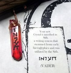 a red glass tube with writing on it sitting next to a piece of paper that says crystal is unwrapped in silver