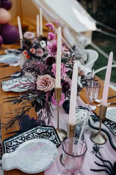 the table is set with candles, plates and napkins for an elegant halloween party