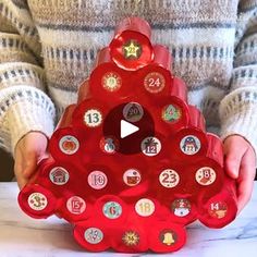 a child holding up a red christmas tree shaped ornament with buttons on it