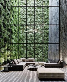 a living room filled with lots of furniture next to a tall wall covered in greenery