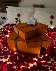 three boxes sitting on top of a bed covered in rose petals