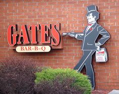 a sign for gates bar - b - q with a man in a suit and tie