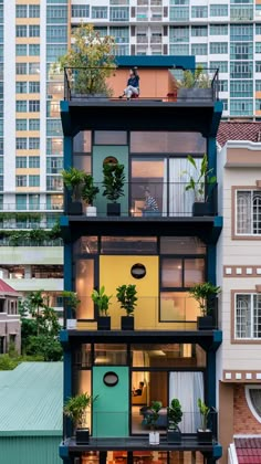 an apartment building with plants growing on the balconies and windows above it is surrounded by high rise buildings