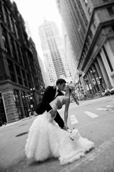 a bride and groom kissing on the street in new york city's financial district