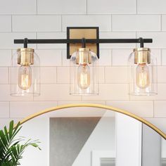 a bathroom vanity light with three lights and a round mirror on the wall above it