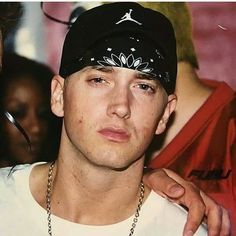 two young men standing next to each other in front of a man wearing a hat