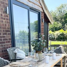 a wooden table sitting on top of a patio next to a brick building with large windows