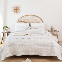 the bed is made with white linens and has a rattan headboard on it