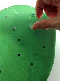 a person is pointing at something on top of a green object with pins in it