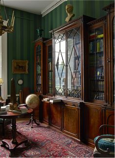 the room has green walls and wooden furniture in it, along with a red rug