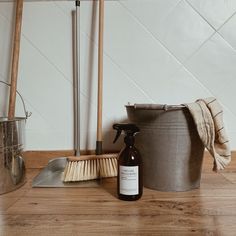 a bottle of cleaner next to a bucket and broom