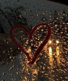 a heart - shaped candle is sitting on the windshield of a car in the rain