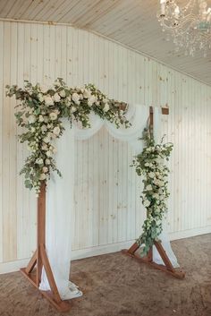 a wedding arch decorated with white flowers and greenery