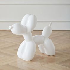 a white balloon dog sitting on top of a hard wood floor