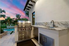 an outdoor kitchen with stainless steel appliances and marble counter tops