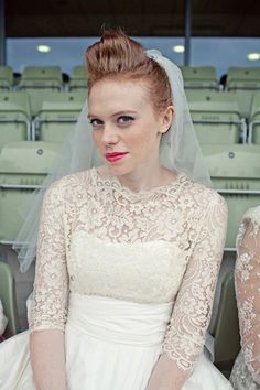 a woman wearing a wedding dress sitting in front of a row of green chairs with her hands on her hips