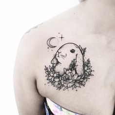 a woman with a tattoo on her shoulder has a bird and flowers around her neck