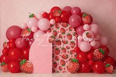 a bunch of balloons and some strawberries in front of a pink backdrop with the number one on it